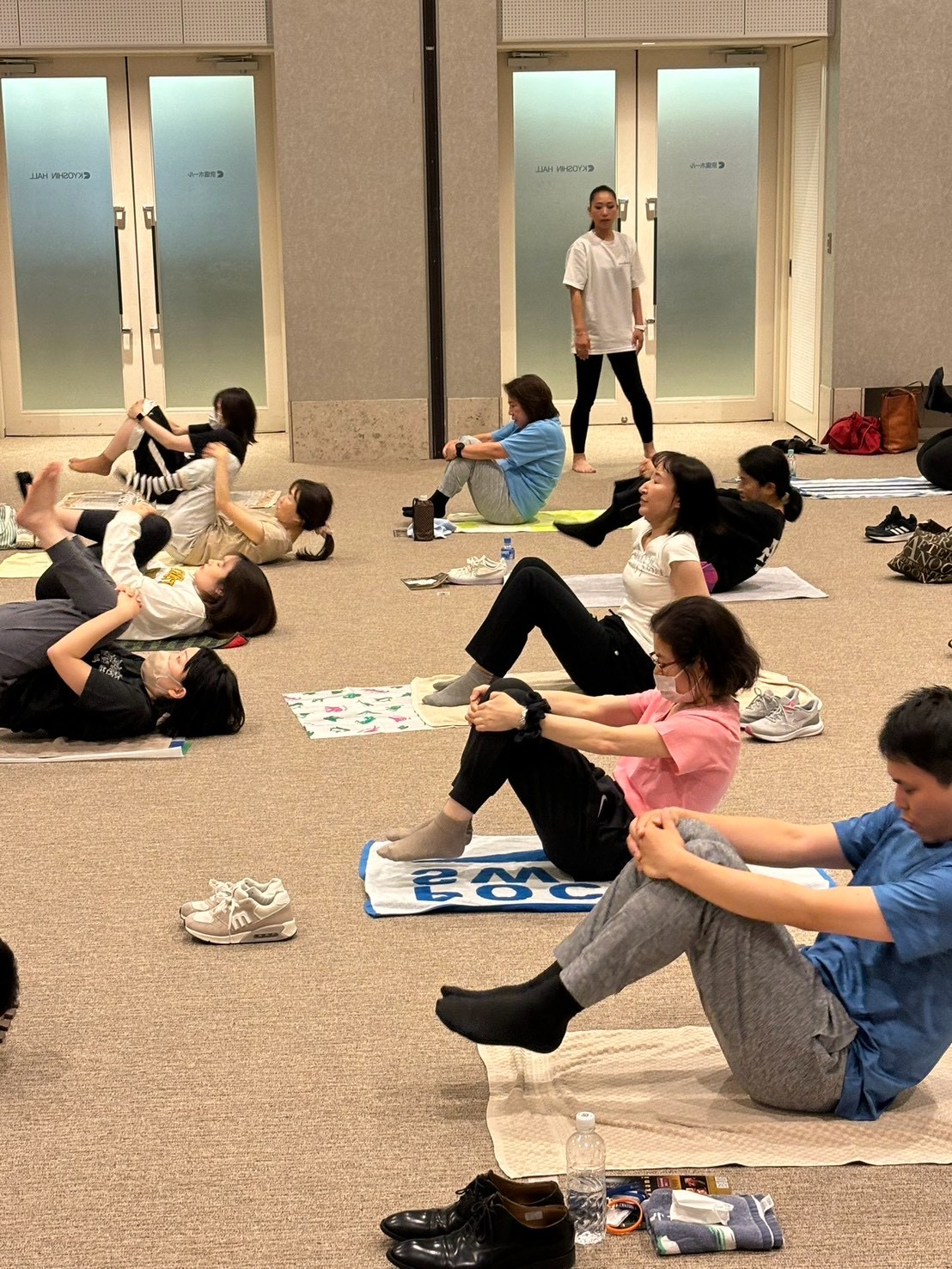 会場の床で体を伸ばす参加者たち