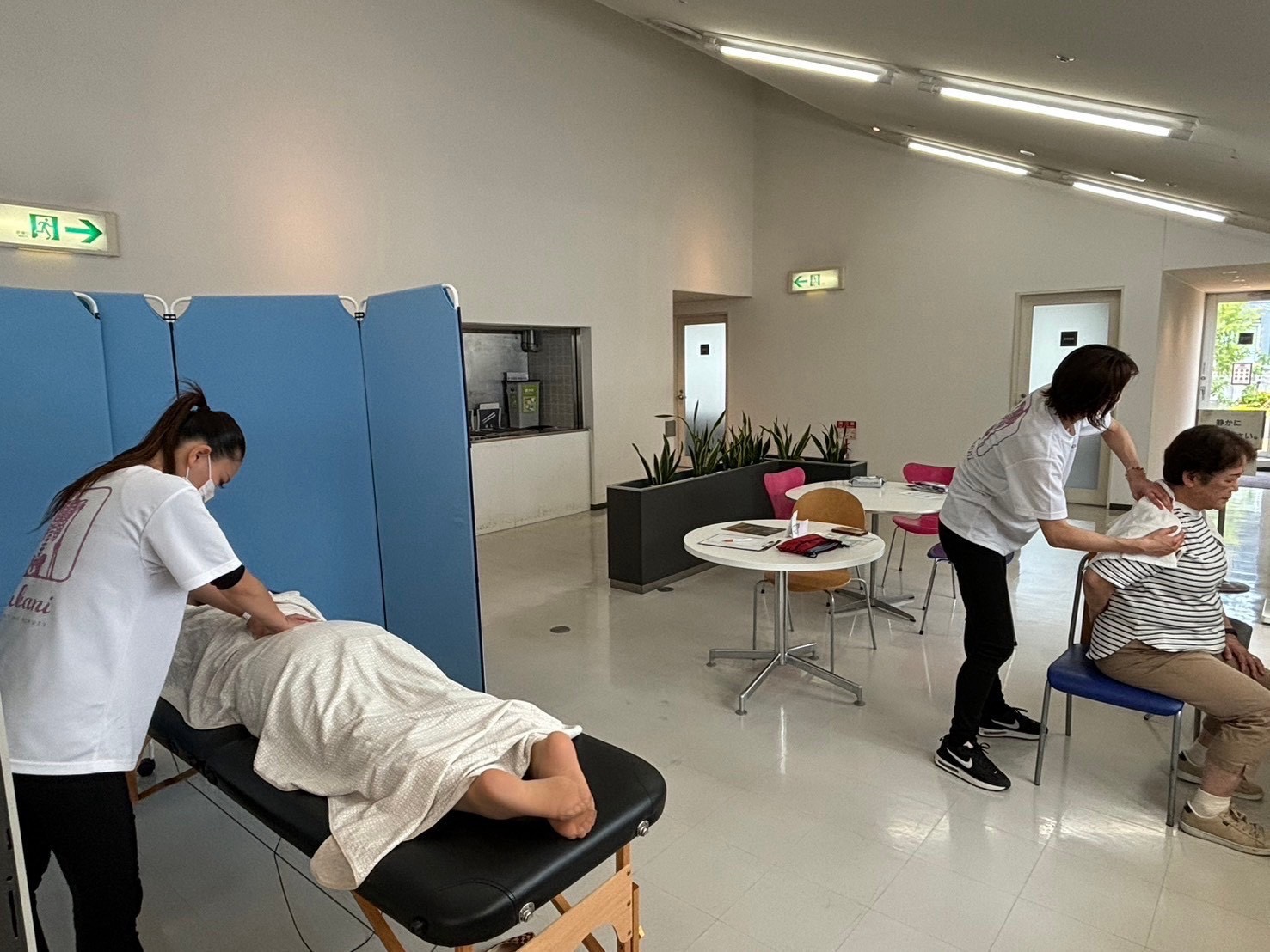 会場で出張施術を行う施術者と、施術を受ける参加者